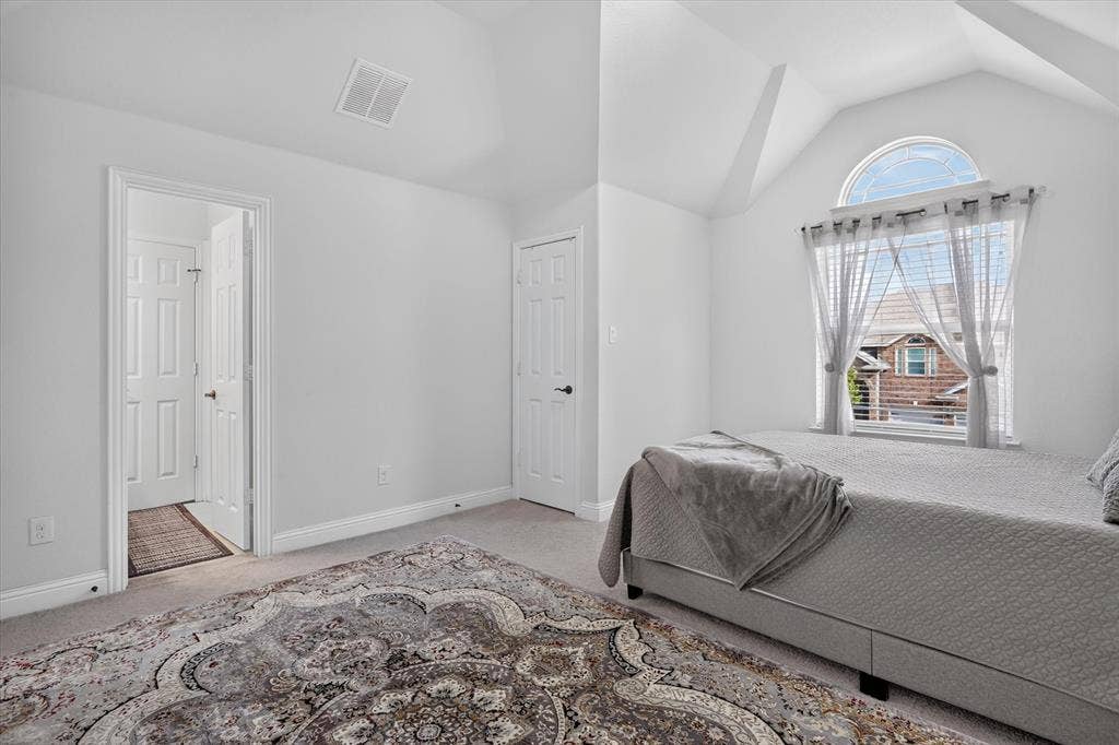 Vaulted ceiling with an arched window, white walls, and wall-to-wall carpeting