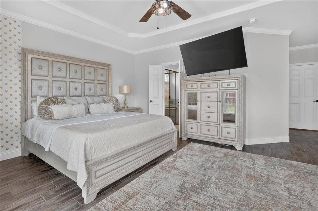 Tray ceiling with crown molding, wood-finish flooring, and built-in wall-mounted television