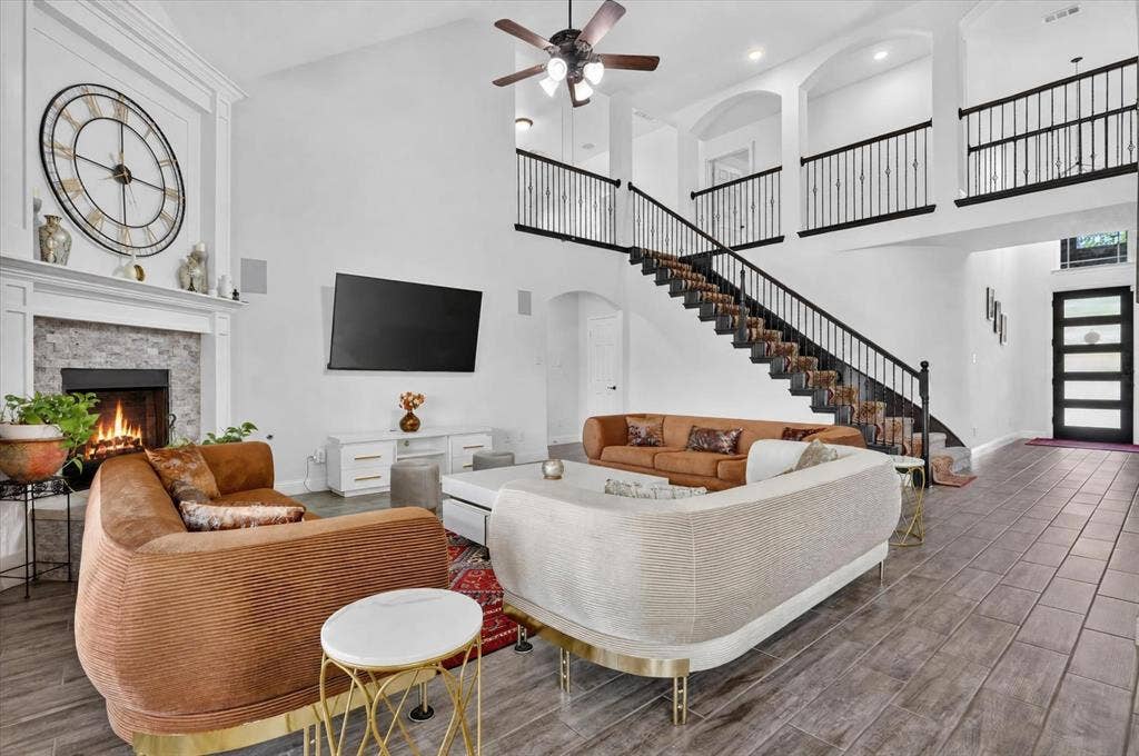 Spacious living area featuring a vaulted ceiling, a fireplace with a stone surround, and wood-finish flooring