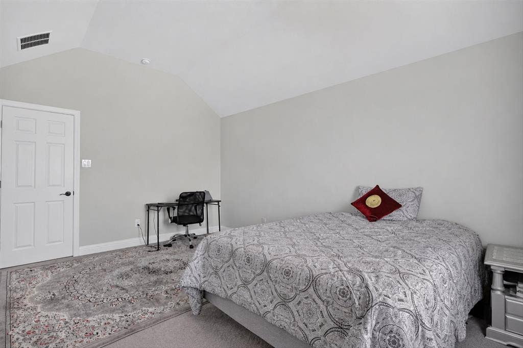 Vaulted ceiling with recessed lighting, white panel door, light gray wall paint, and gray carpeting