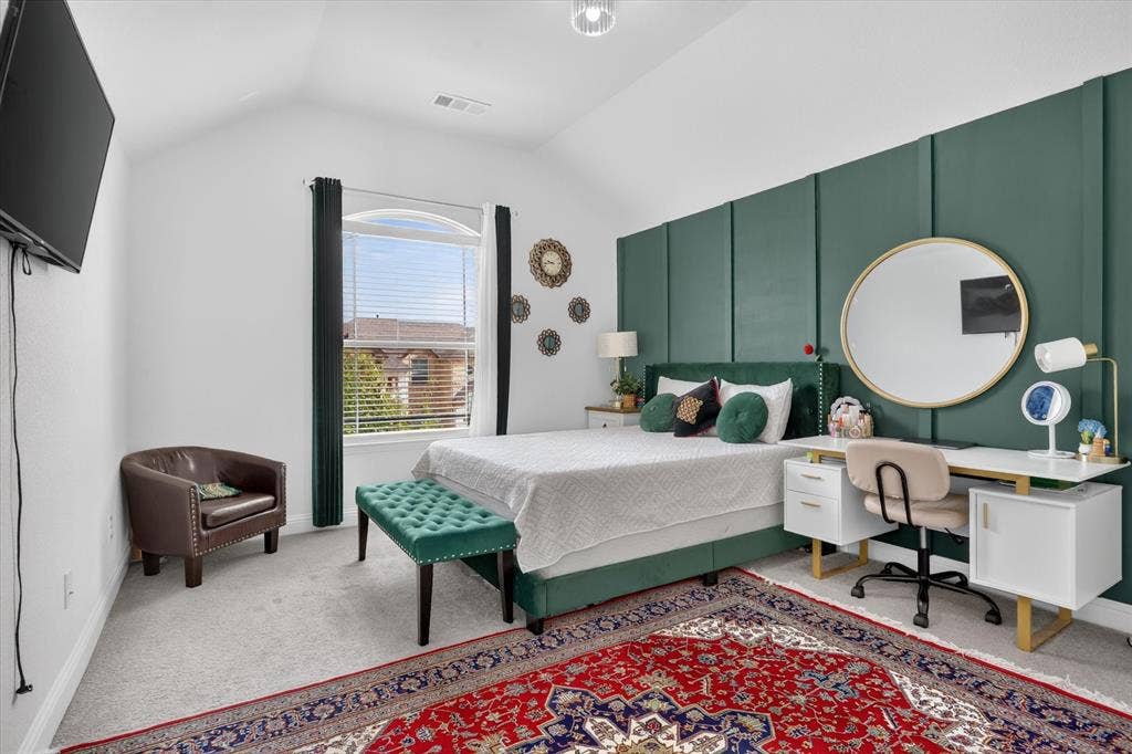 Vaulted ceiling with an arched window, featuring carpet flooring and a built-in paneled wall