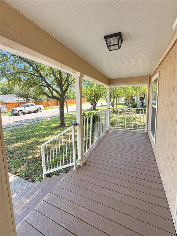1203 N College Street, McKinney, TX 75069 Covered front porch featuring wood-finish decking, white railings, and a flush-mount outdoor light fixture