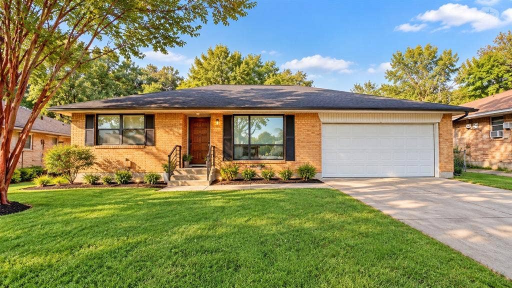4331 Kolloch Drive, Dallas, TX 75216 Brick exterior with dark shutters, attached garage, concrete driveway, and mature landscaping