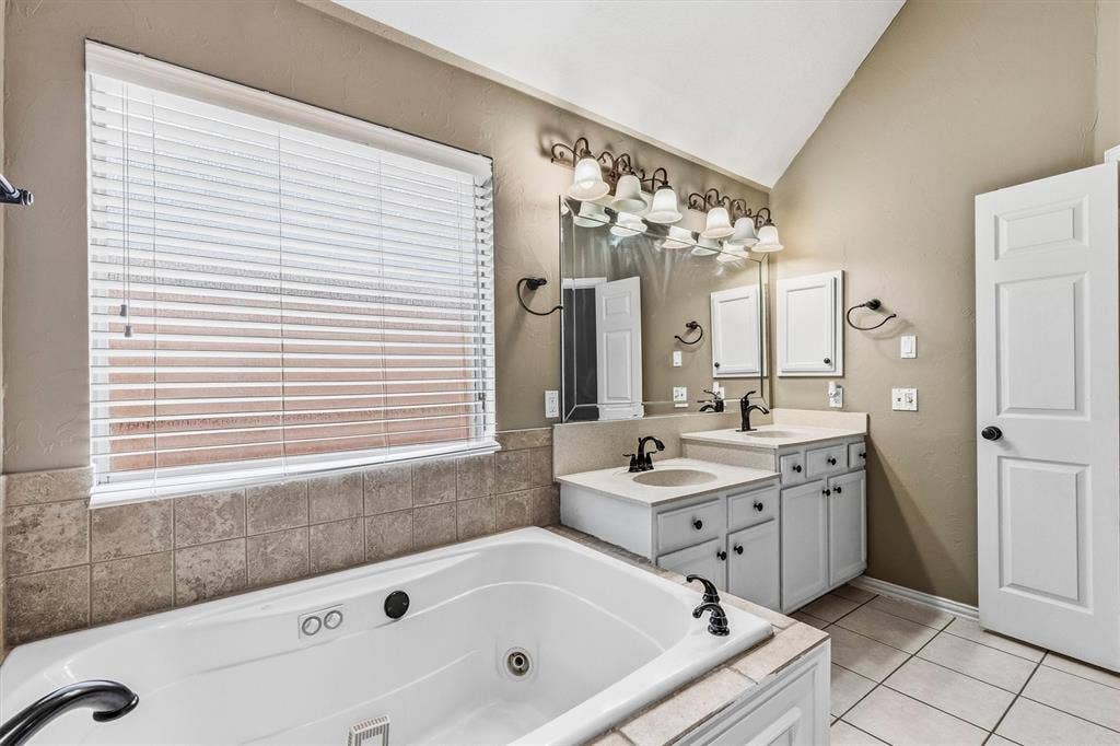 3916 Montrose Drive, Plano, TX 75025 Jetted bathtub with tile surround, dual vanities with integrated sinks, and individual mirrors