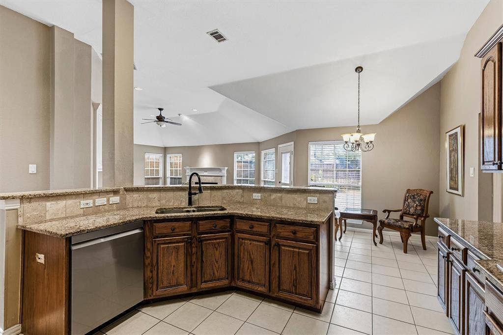3916 Montrose Drive, Plano, TX 75025 Kitchen featuring wood cabinetry, stainless steel dishwasher, a black gooseneck faucet, light granite countertops, and tile flooring