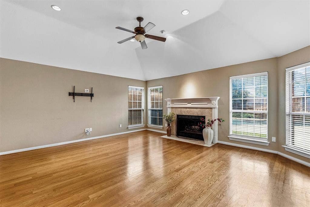 3916 Montrose Drive, Plano, TX 75025 Spacious living area featuring gleaming wood-finish flooring, vaulted ceilings with recessed lighting, and a ceiling fan