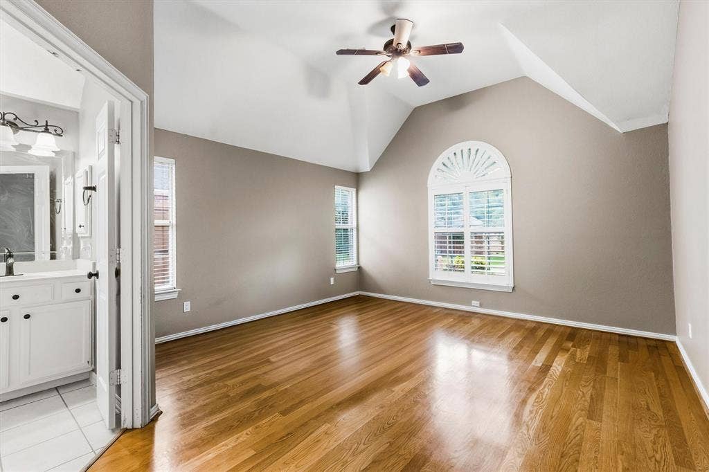3916 Montrose Drive, Plano, TX 75025 Vaulted ceiling, wood-finish flooring, ceiling fan, arched window with plantation shutters, and a vanity with a rectangular mirror