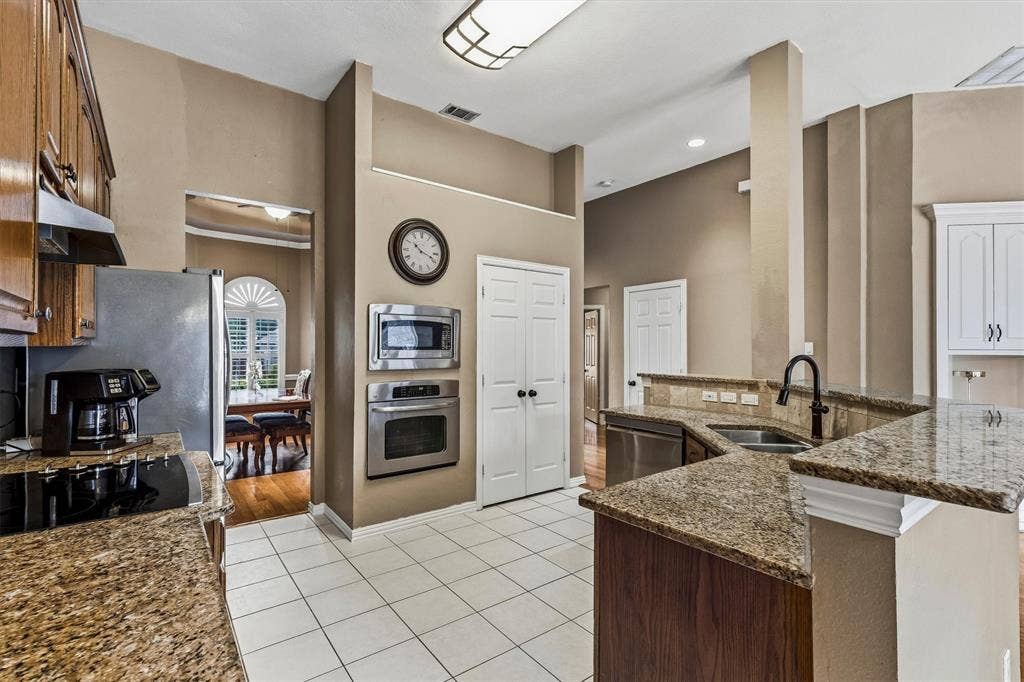 3916 Montrose Drive, Plano, TX 75025 Stainless steel appliances, built-in microwave, wall oven, granite countertops, and white tile flooring
