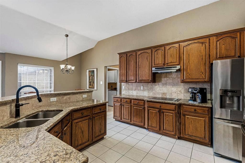 3916 Montrose Drive, Plano, TX 75025 Kitchen featuring wood cabinetry, granite countertops, a double basin sink with a black fixture, stainless steel appliances, and tile flooring