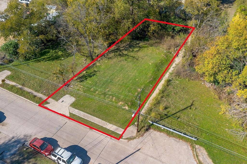 2433 52nd Street, Dallas, TX 75216 Expansive residential lot featuring a manicured lawn, mature tree line bordering the perimeter, and direct street access