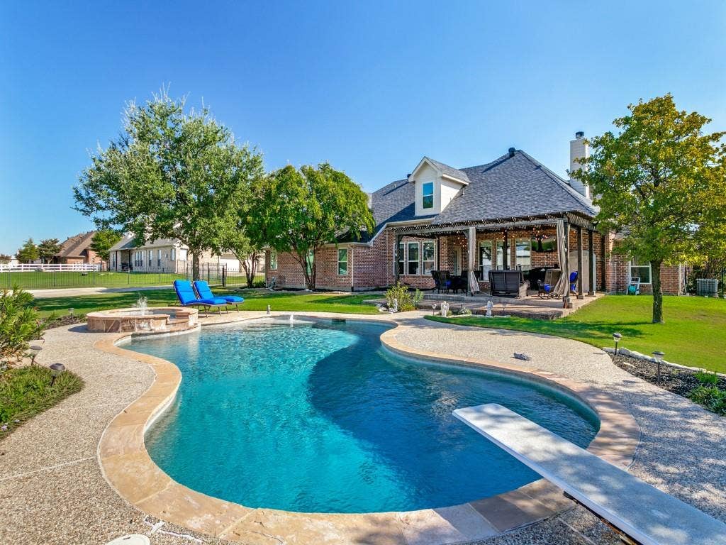 508 Singing Quail Trail, Haslet, TX 76052 Curved swimming pool with a diving board, integrated hot tub, and a covered patio featuring a wood beam roof