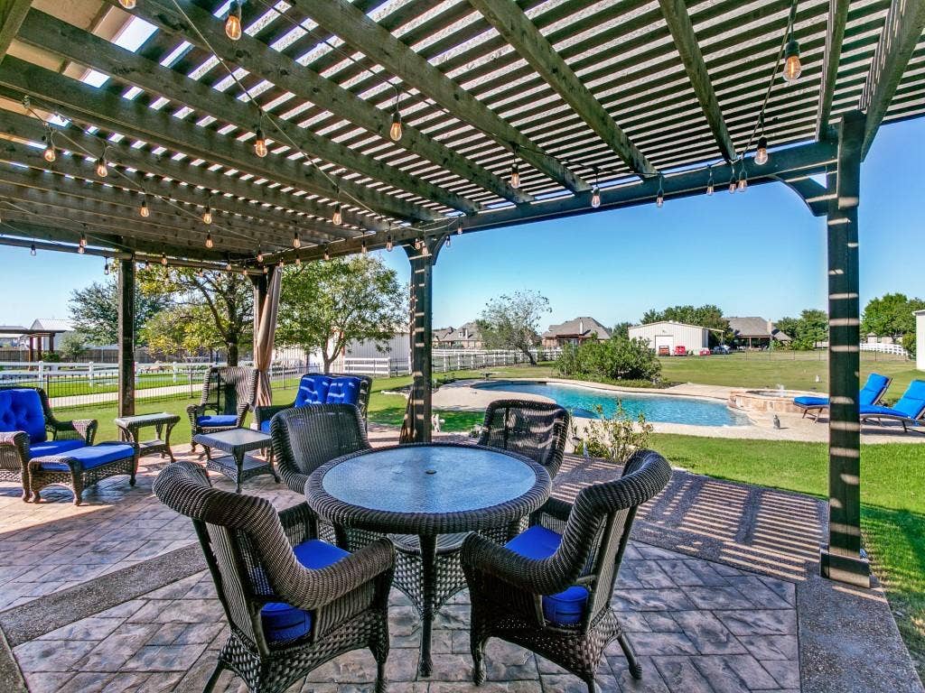 508 Singing Quail Trail, Haslet, TX 76052 Expansive outdoor living area featuring a covered patio with string lighting, stamped concrete flooring, a fenced backyard, and a built-in swimming pool