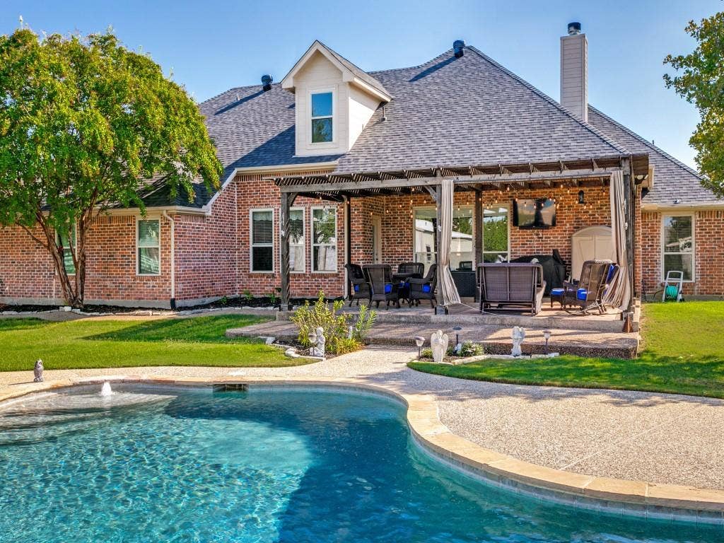 508 Singing Quail Trail, Haslet, TX 76052 Brick exterior with a dormer window, covered patio with a pergola, and a private swimming pool with a water feature