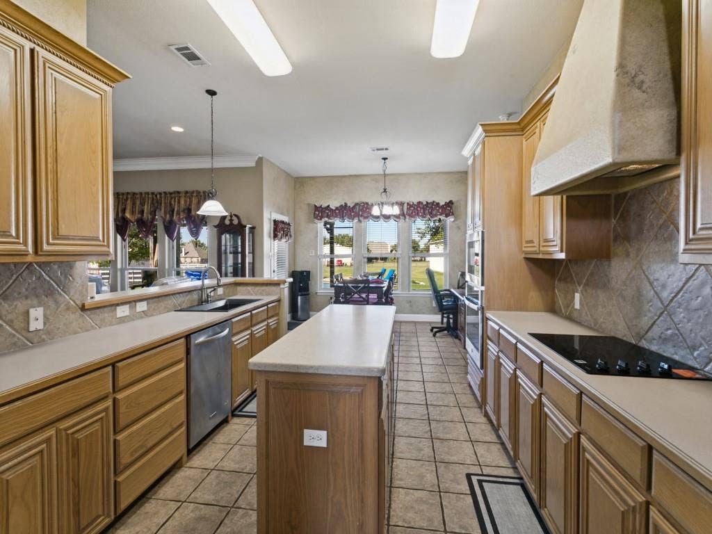 508 Singing Quail Trail, Haslet, TX 76052 Kitchen featuring wood cabinetry, stone-look countertops, a built-in cooktop, tile flooring, and a stone-clad range hood