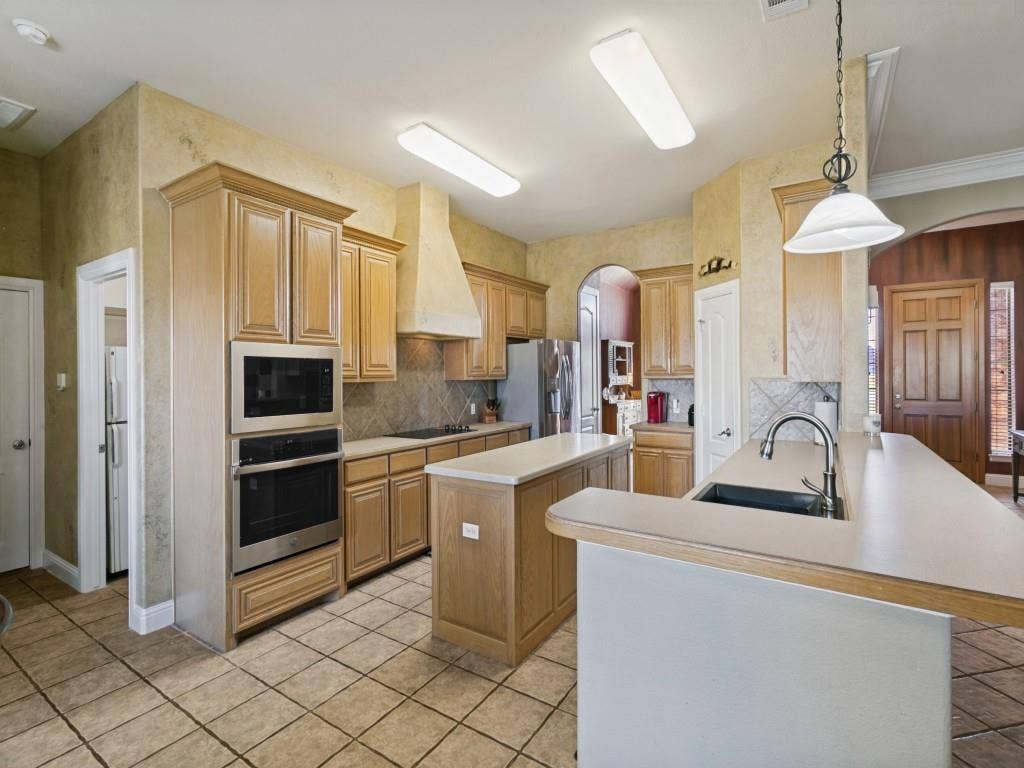 508 Singing Quail Trail, Haslet, TX 76052 Kitchen with light wood cabinetry, a central island, tile flooring, stainless steel built-in appliances, and a double basin sink