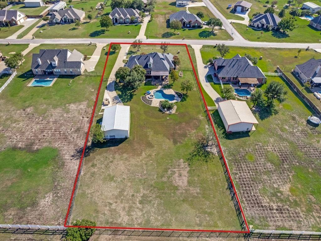 508 Singing Quail Trail, Haslet, TX 76052 Expansive property featuring a residence with a dark shingled roof, a curvilinear swimming pool, a detached outbuilding with a light-colored roof, and perimeter fencing