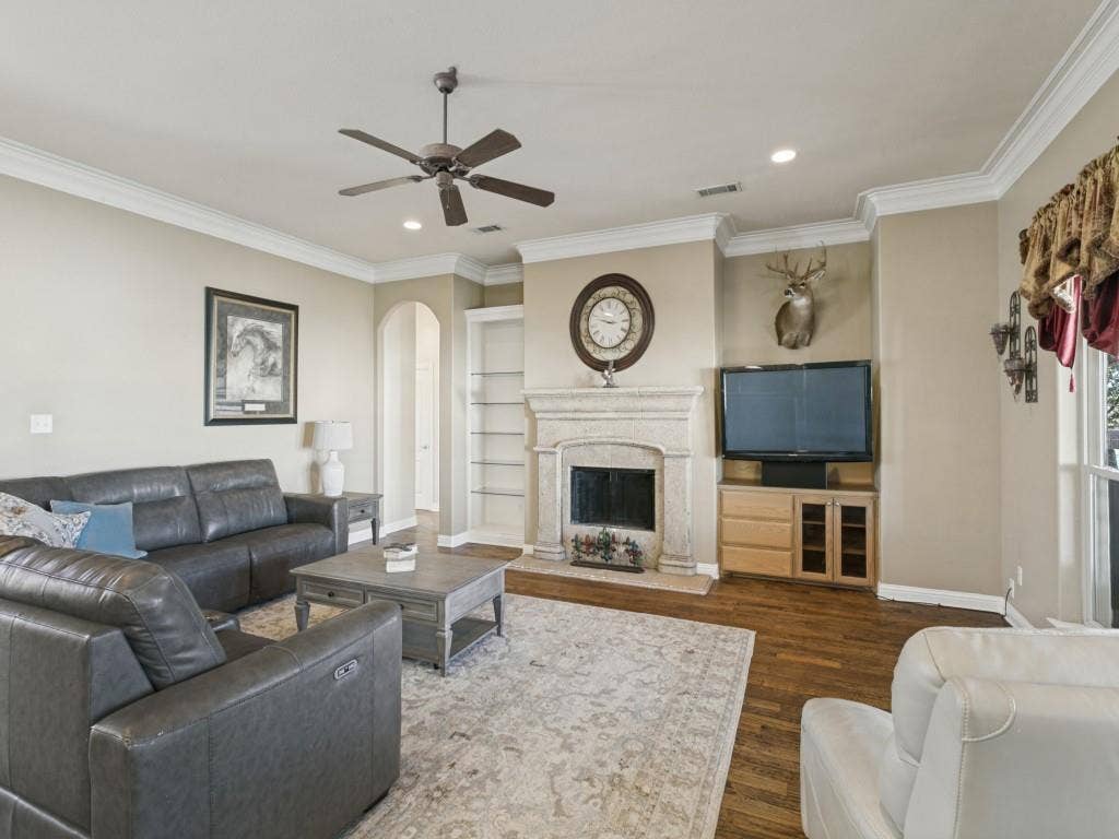 508 Singing Quail Trail, Haslet, TX 76052 Elegant living room showcasing a fireplace with white surround and mantel, hardwood flooring, crown molding, recessed lighting, and a ceiling fan