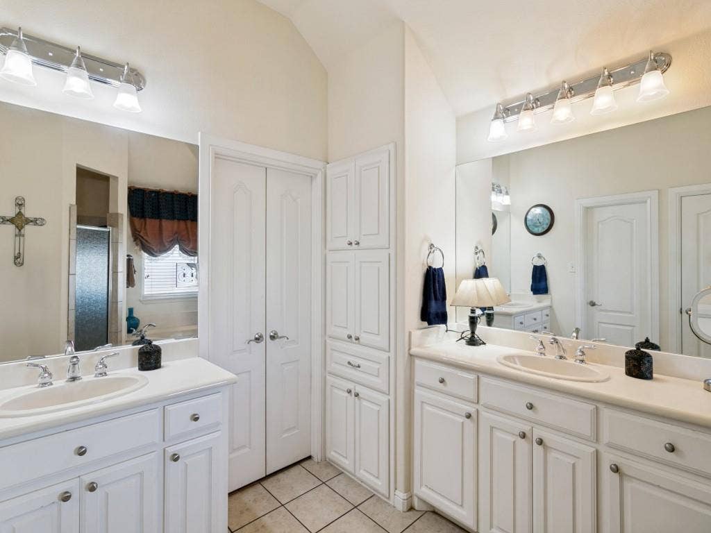 508 Singing Quail Trail, Haslet, TX 76052 Dual vanities with integrated sinks, extensive white cabinetry, large mirrors, built-in storage tower, and tiled flooring