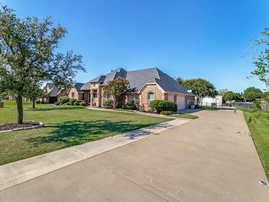 508 Singing Quail Trail, Haslet, TX 76052 Brick facade, multi-car concrete driveway, attached garage, mature landscaping, and an expansive lawn
