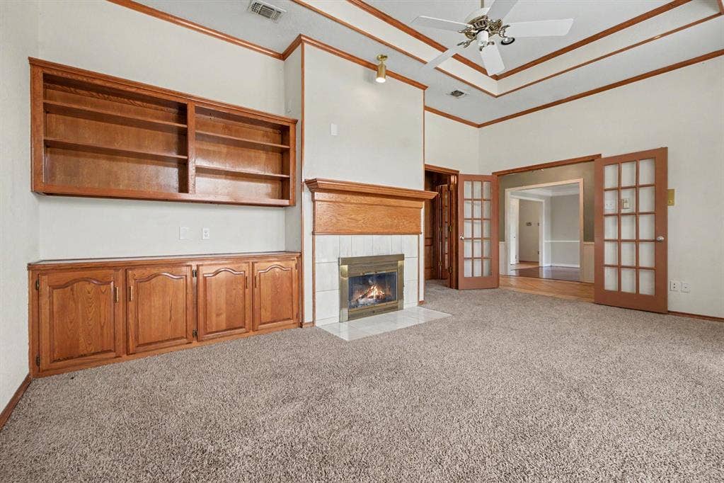 3313 Anchor Drive, Plano, TX 75023 Built-in wood cabinetry and shelving, a fireplace with a tile surround and wood mantel, a coffered ceiling with a ceiling fan, and French doors