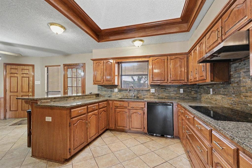 3313 Anchor Drive, Plano, TX 75023 Kitchen featuring wood cabinetry, stone countertops, a tile backsplash, and a coffered ceiling with wood trim