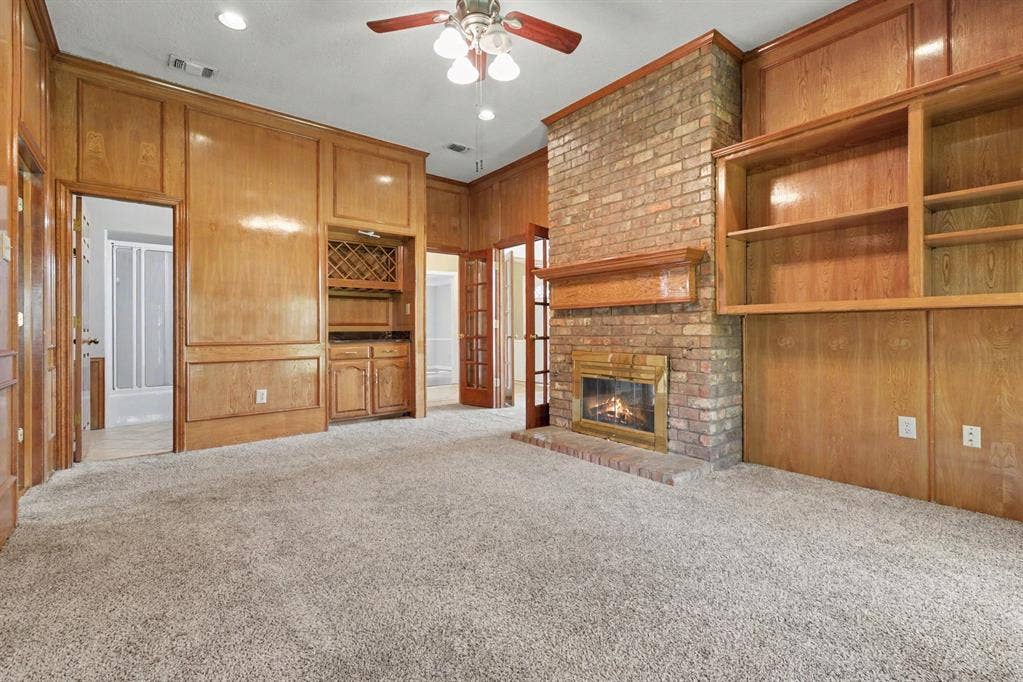 3313 Anchor Drive, Plano, TX 75023 Wood paneling throughout, brick fireplace with mantel, built-in shelving, built-in cabinetry with wine rack, and recessed lighting