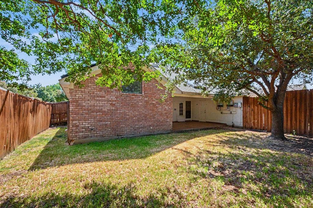 3313 Anchor Drive, Plano, TX 75023 Expansive backyard space featuring mature trees, a covered patio, and a brick exterior