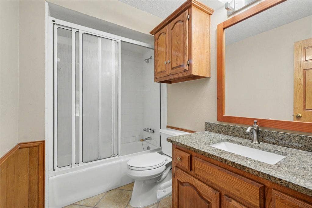 3313 Anchor Drive, Plano, TX 75023 Bathroom featuring a built-in vanity with a granite-style countertop, undermount sink, and wood-finish cabinetry