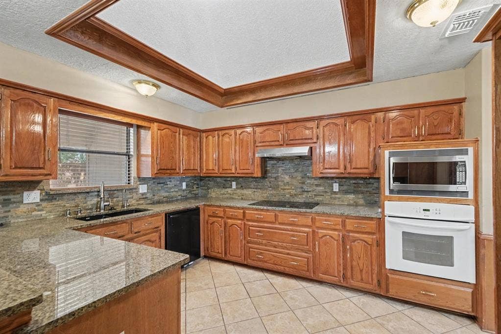 3313 Anchor Drive, Plano, TX 75023 Kitchen featuring wood cabinetry, built-in oven, built-in microwave, stone countertops, and tile flooring
