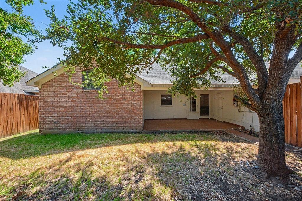 3313 Anchor Drive, Plano, TX 75023 Expansive backyard featuring a mature tree, brick exterior, wood fence, and a covered patio