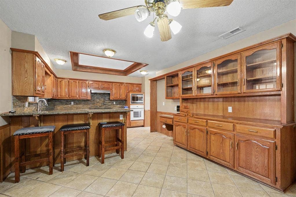 3313 Anchor Drive, Plano, TX 75023 Kitchen featuring extensive wood cabinetry, tile flooring, built-in double oven, built-in microwave, and a ceiling fan