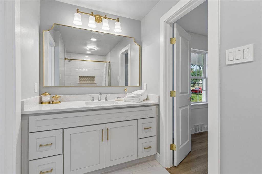 11864 Cold Harbor Lane, Dallas, TX 75244 Jack and Jill bathroom with a shower/tub combo, glossy tile surround, decorative niche, and brushed gold fixtures for a polished touch.
