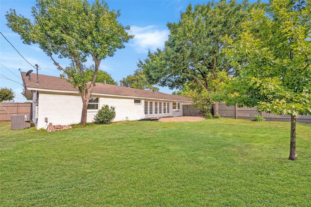 11864 Cold Harbor Lane, Dallas, TX 75244 Classic white brick ranch home with a sprawling green backyard, mature shade trees, and a French door entry onto the patio.