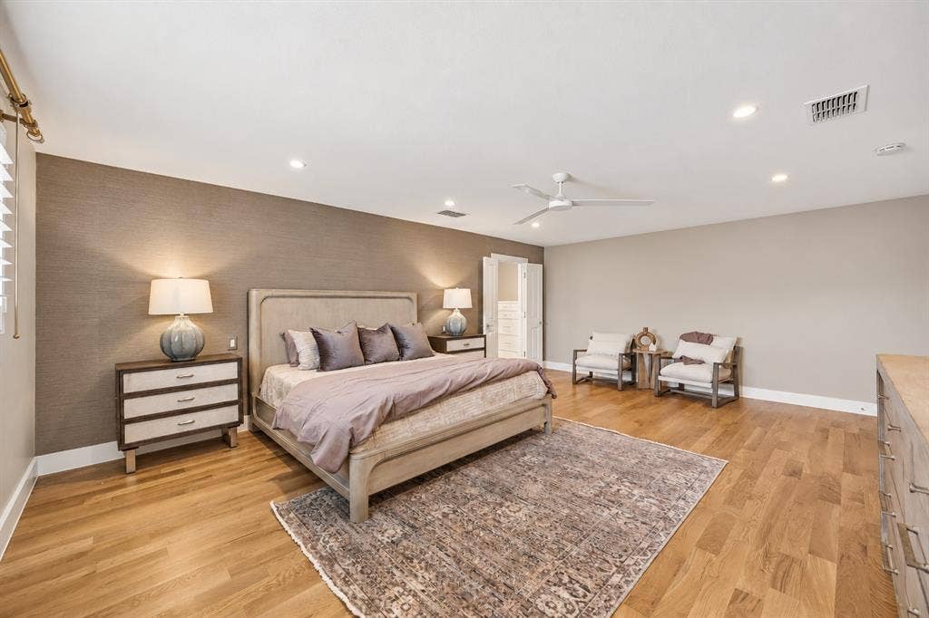 Spacious room featuring wood-finish flooring, a textured accent wall, recessed lighting, and a white ceiling fan