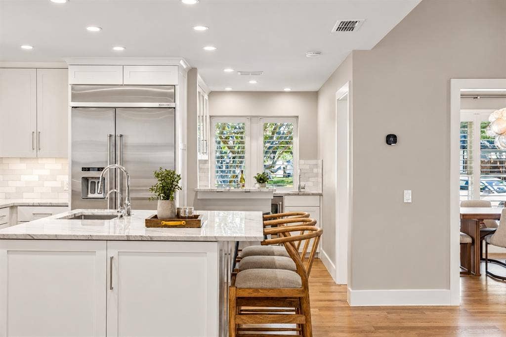 Kitchen-wet bar area perfect for serving, entertaining, and additional storage. Features sink, Kitchenaid wine cooler, and 2024 ice machine.