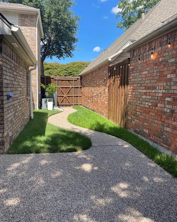 1944 Vantage Drive, Plano, TX 75075 Expansive exposed aggregate walkway with a curved design, bordered by lush green landscaping