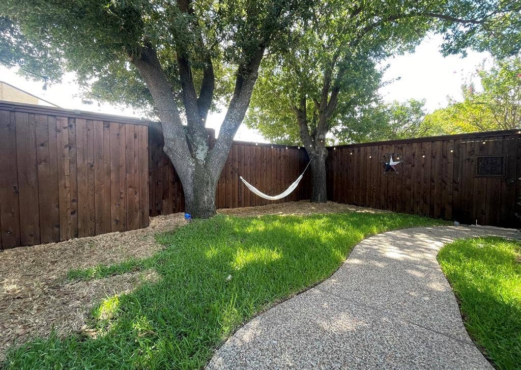 1944 Vantage Drive, Plano, TX 75075 Private backyard with a stained wood fence, mature trees, and a curved concrete pathway