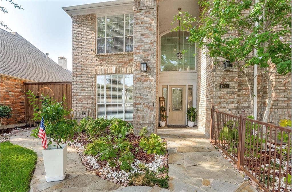 1944 Vantage Drive, Plano, TX 75075 Brick exterior with multiple windows, arched entryway, and a stone walkway