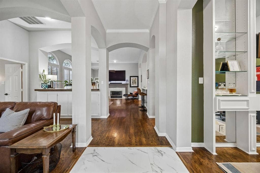 3104 Congress Avenue, Plano, TX 75025 Open-concept living space featuring soaring ceilings with architectural arches, white structural columns, and rich wood-finish flooring throughout