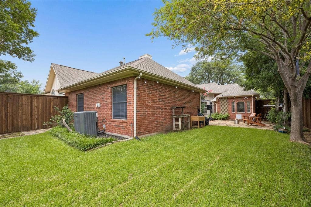 3104 Congress Avenue, Plano, TX 75025 Expansive lawn area with a wood privacy fence, mature trees, and a brick exterior building