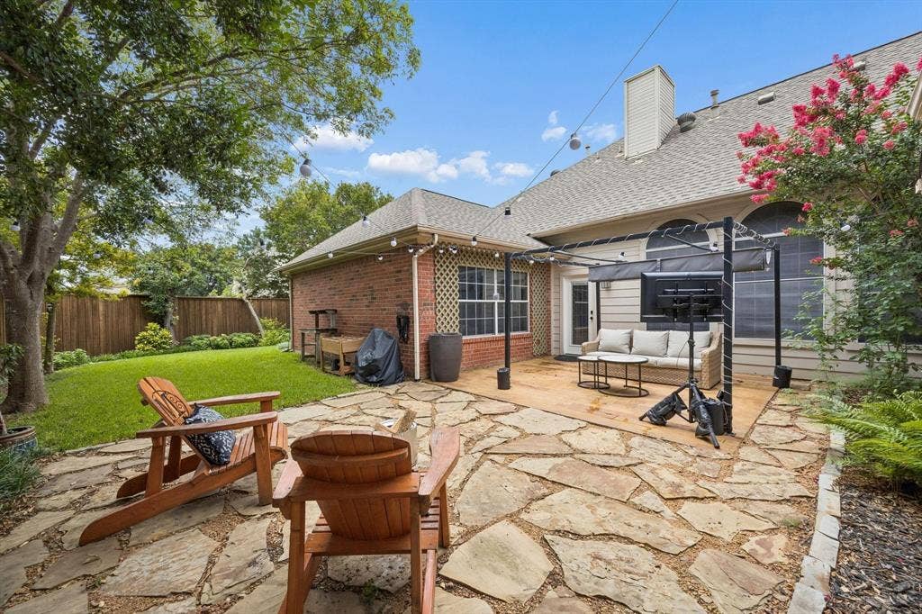 3104 Congress Avenue, Plano, TX 75025 Expansive backyard featuring a stone patio, lush lawn, mature trees, and a pergola-covered patio area