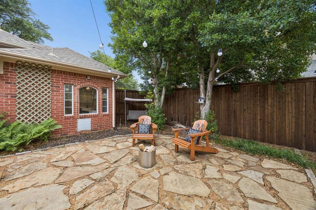 3104 Congress Avenue, Plano, TX 75025 Stone patio featuring a brick exterior with an arched window, mature trees, and a wood privacy fence