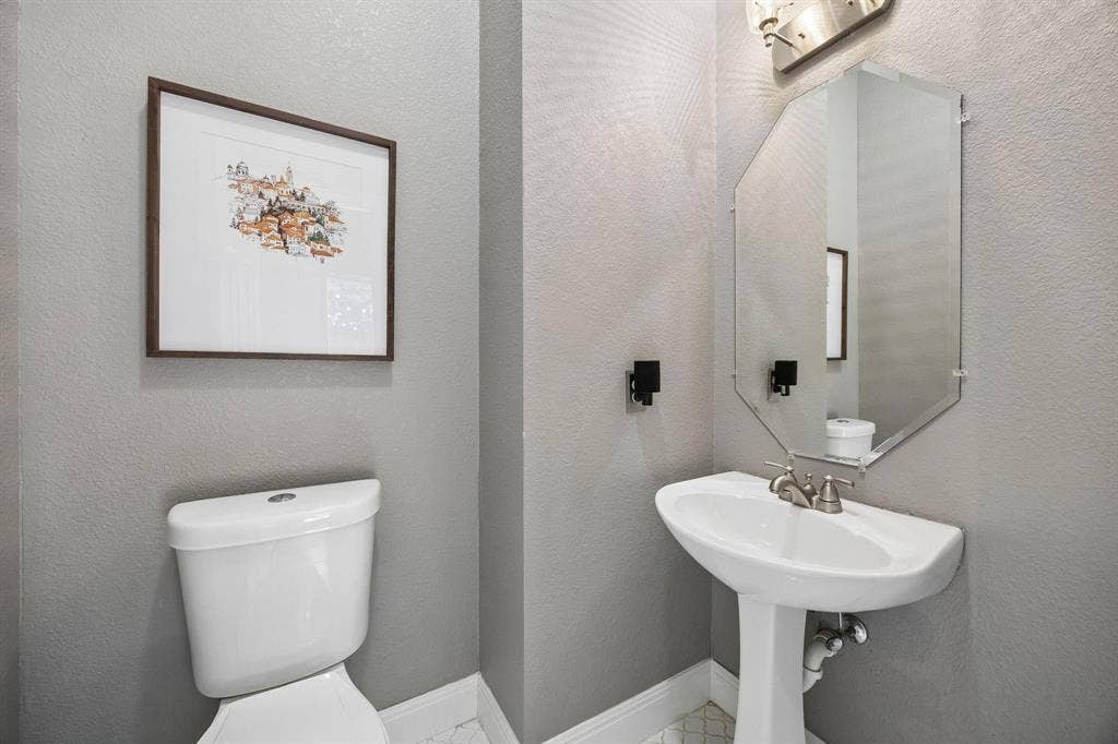 3104 Congress Avenue, Plano, TX 75025 Pedestal sink with brushed nickel faucet, beveled mirror, and wall-mounted vanity lighting