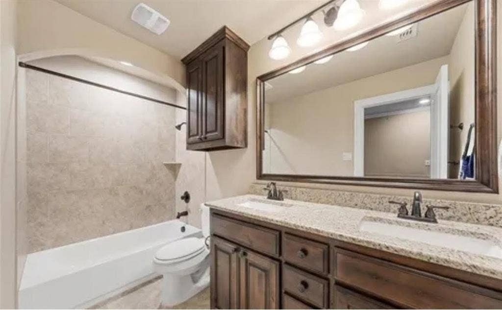 2313 Therese, Waco, TX 76712 Dual vanity with granite countertops, rich wood cabinetry, and a framed mirror