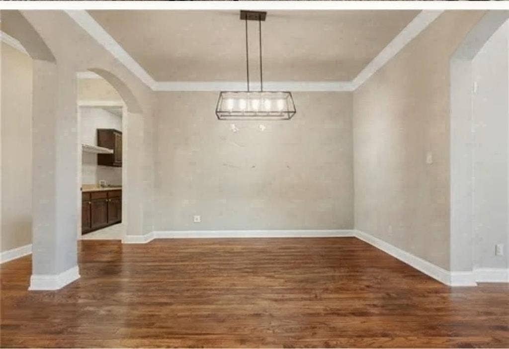 2313 Therese, Waco, TX 76712 Hardwood flooring throughout, featuring crown molding, a modern linear chandelier, and arched doorways