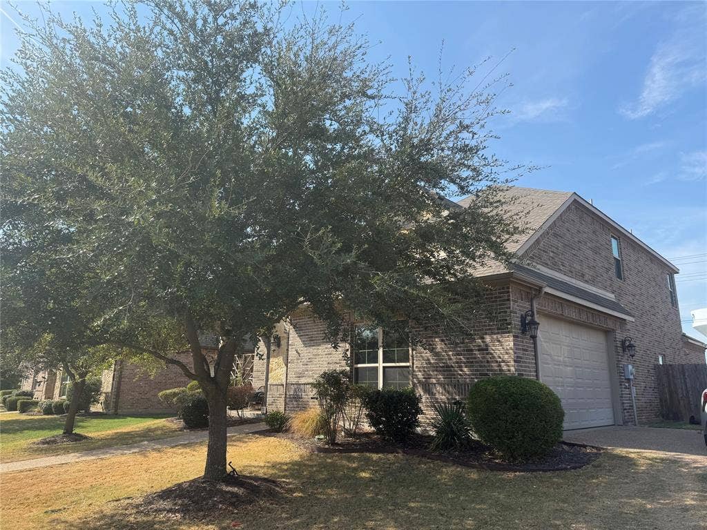 2313 Therese, Waco, TX 76712 Brick exterior facade with a two-car garage, mature landscaping, and a well-maintained roof