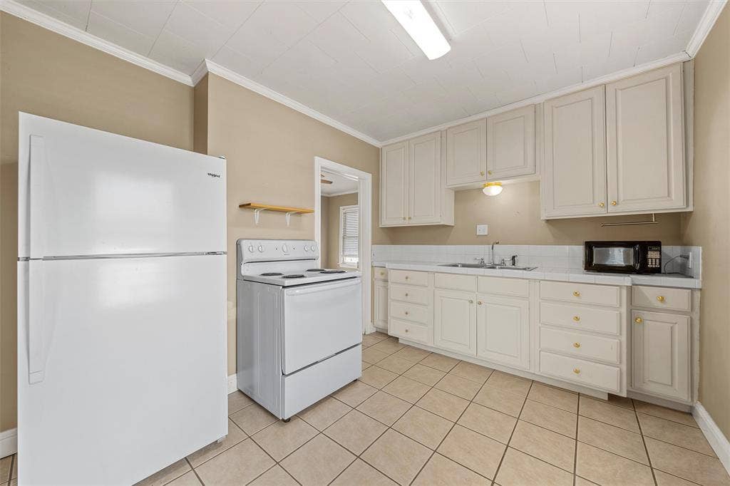 2424 Austin Avenue, Waco, TX 76701 Kitchen featuring white cabinetry with gold-toned hardware, white appliances, a tile backsplash, and tile flooring