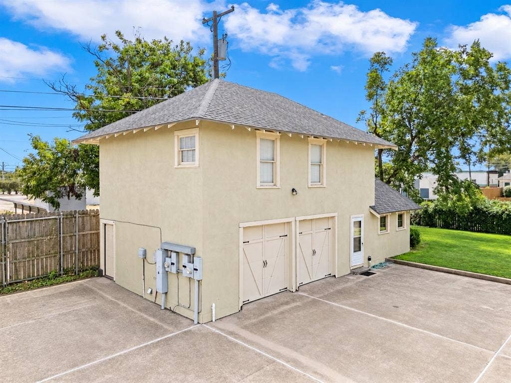2424 Austin Avenue, Waco, TX 76701 Two-story structure with stucco exterior, two garage bays, multiple windows, and a paved parking area