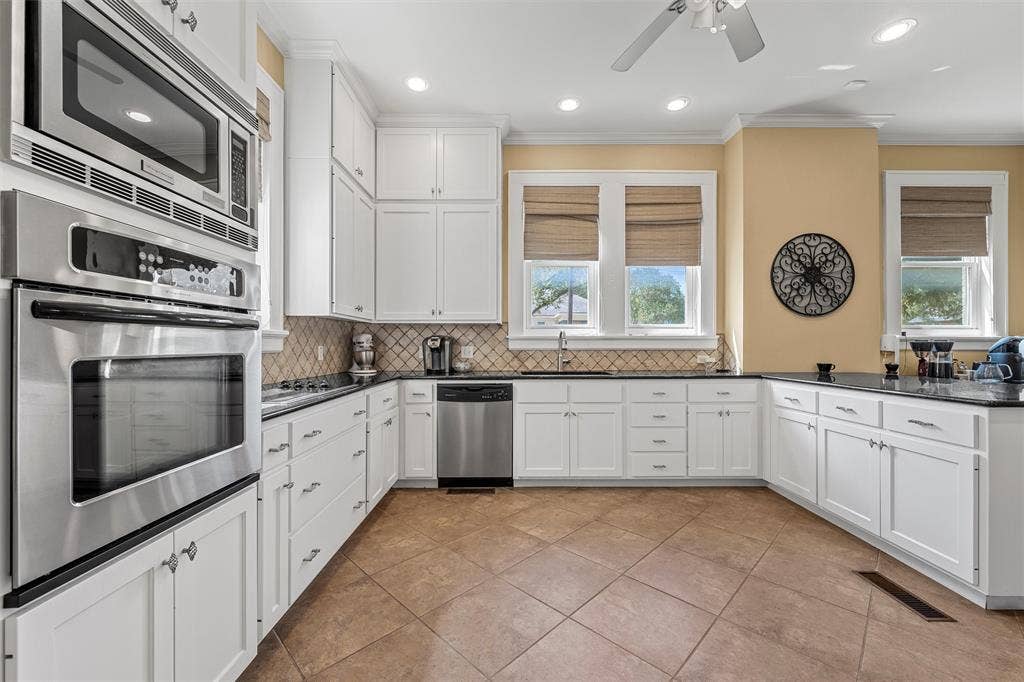 2424 Austin Avenue, Waco, TX 76701 Kitchen featuring white cabinetry, stainless steel appliances, dark countertops, a patterned tile backsplash, and tile flooring