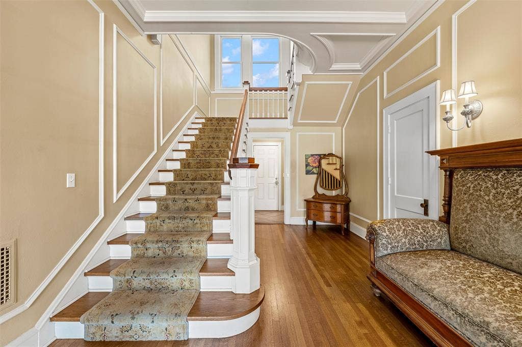 2424 Austin Avenue, Waco, TX 76701 Hardwood flooring, custom wall molding, grand staircase with carpet runner, wall sconce lighting, and high ceilings